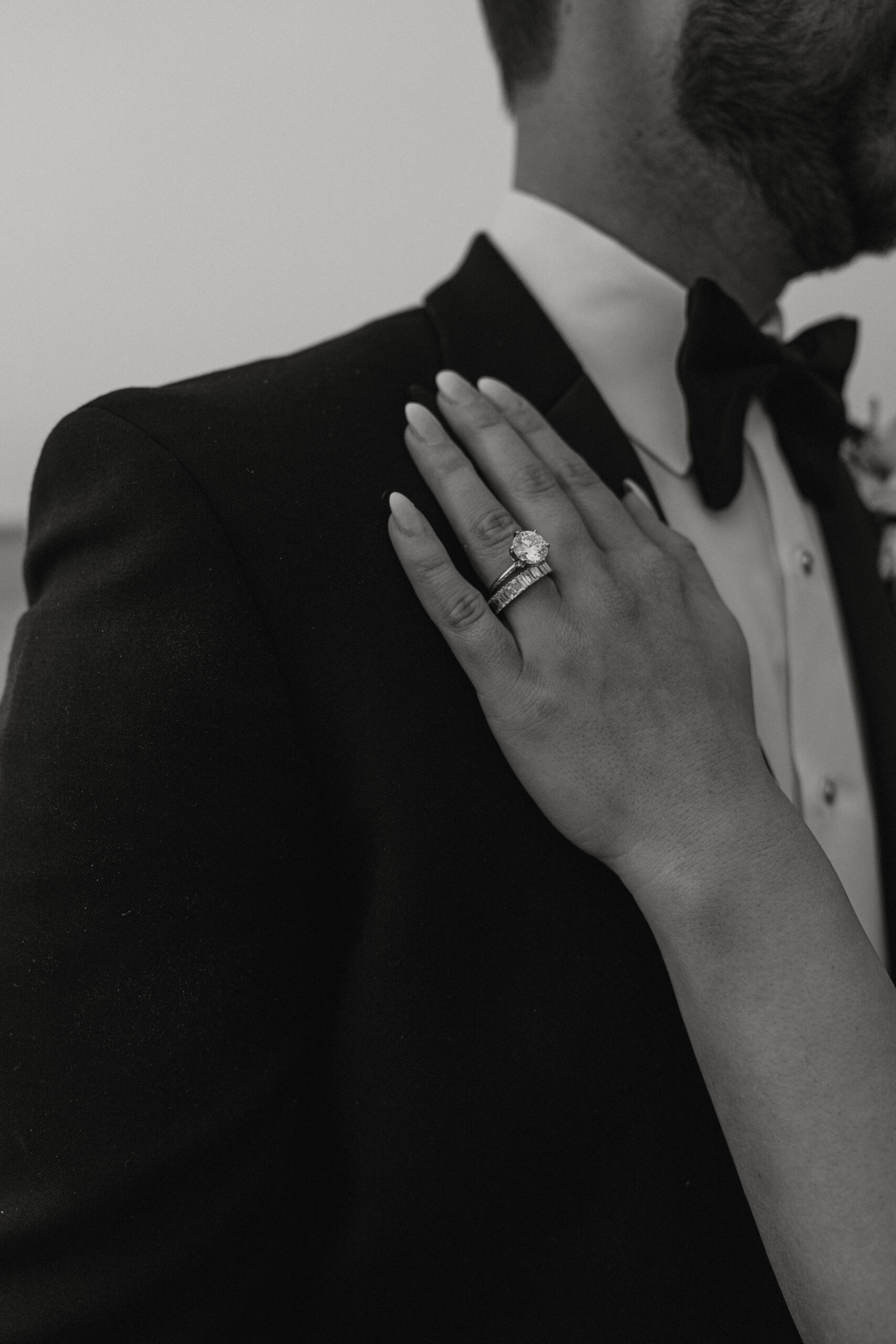 Bride is placing her hand on a grooms chest showing off her ring